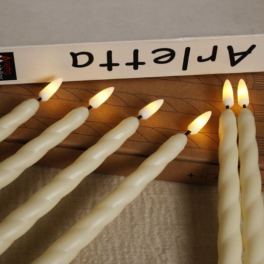Set of six LED long candle lights with realistic flame effect placed beside a book