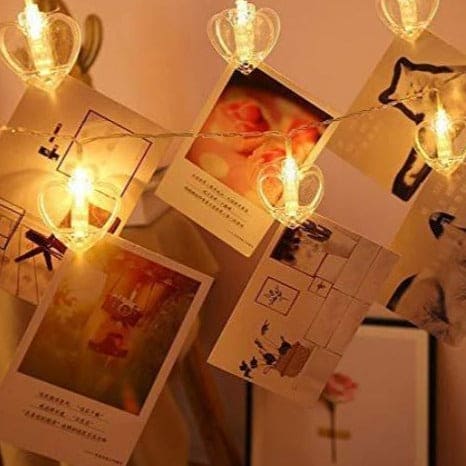 Clarify.pk LED photo clip string lights with heart-shaped clips holding photos on a warm background