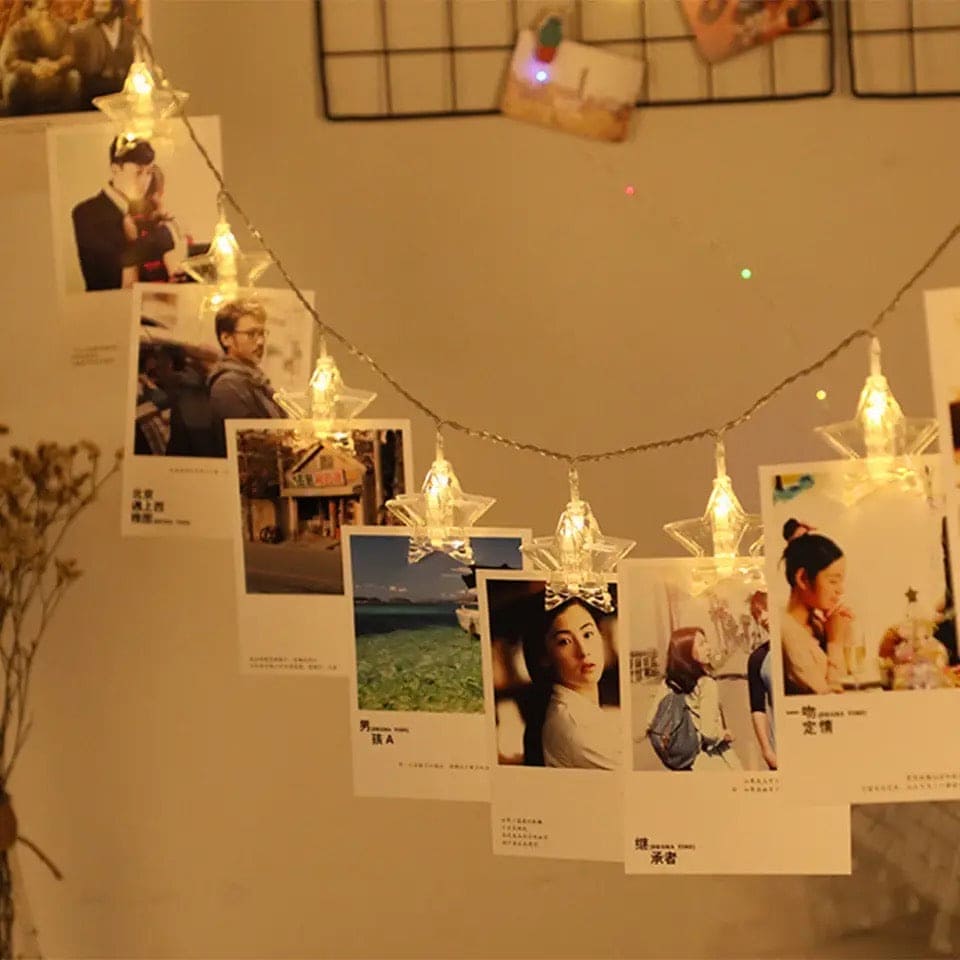 Clarify.pk LED photo clip string lights with star-shaped warm white LED bulbs holding photos on a wall