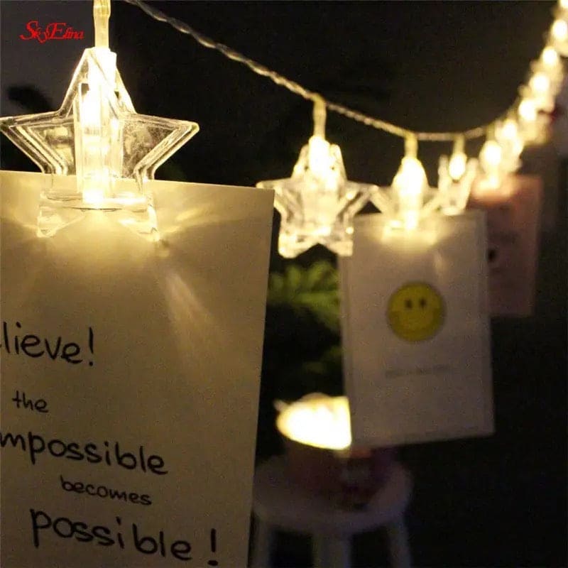 Clear star-shaped LED photo clip string lights holding notes and photos in a cozy indoor setting