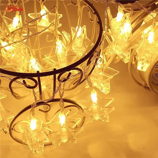 Warm glowing LED photo clip string lights with clear star-shaped clips hanging on a decorative metal stand