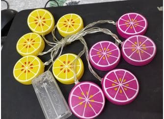 Lemon slice string lights with yellow and pink citrus-shaped LED decorations on clear wire