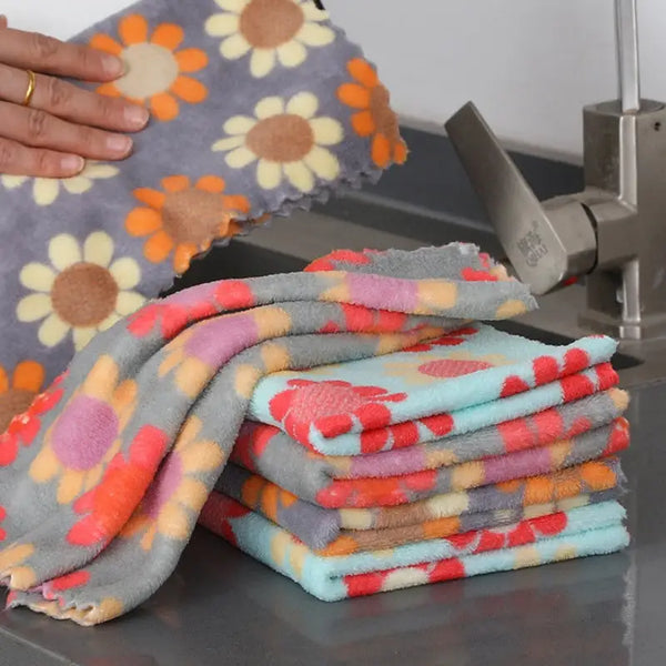 Stack of colorful floral cotton face towels with daisy print by sink hand holding one towel