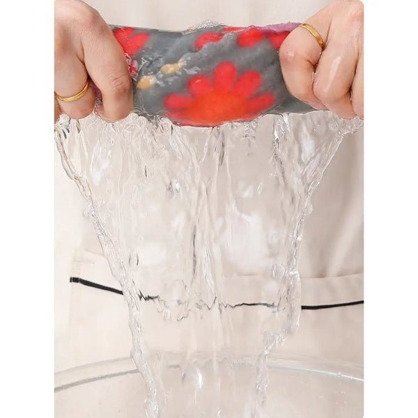 Hands wringing water from floral cotton face towels with red flower print pouring into a glass bowl