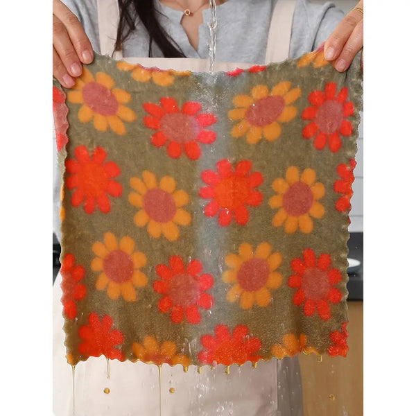 Clarify pk floral cotton face towels with orange and yellow daisy print held wet to show absorbency