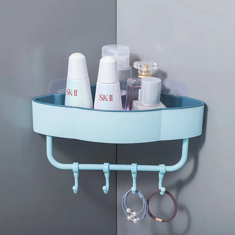 Blue wall-mounted corner shower shelf with hooks holding toiletries and hair ties on bathroom wall