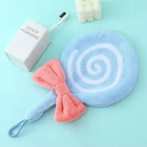Blue and white swirled lollipop design bathroom towel with a pink bow on a light blue background