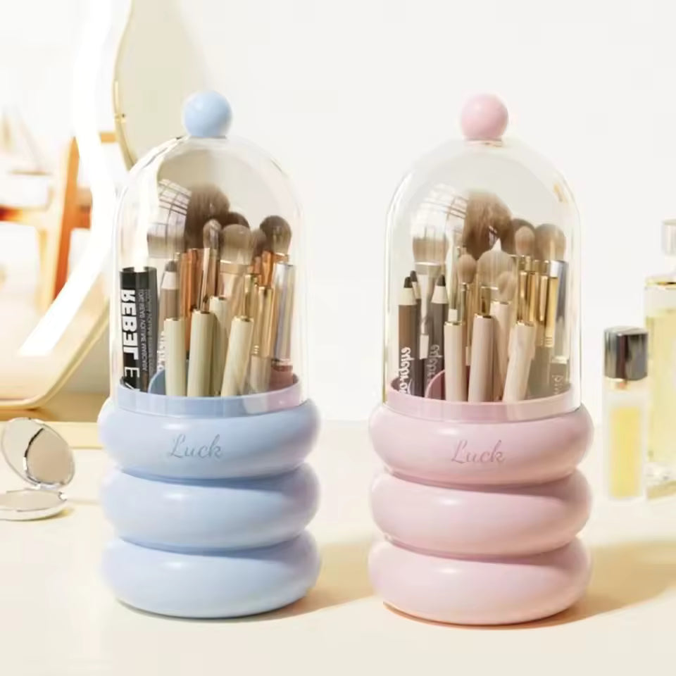 Blue and pink dustproof makeup organizer with lid holding brushes and cosmetics on a vanity