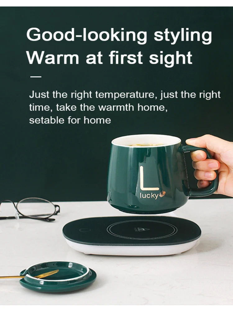 Green ceramic mug with warmer on white surface held by hand near glasses and small plate
