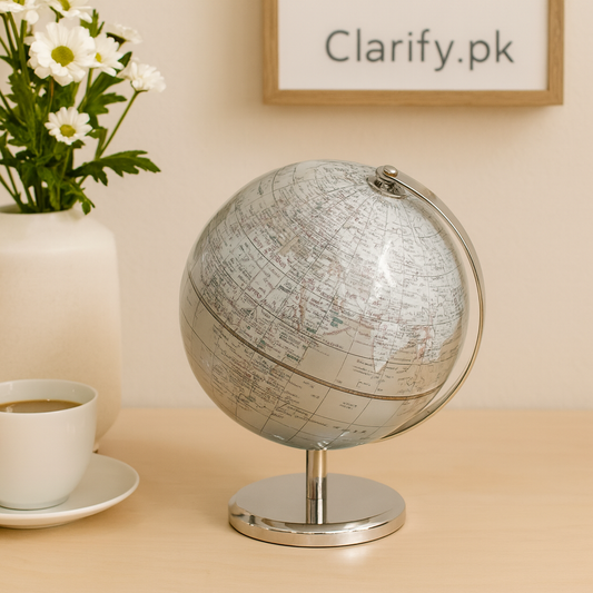 Luxury decorative world globe with silver stand on wooden desk near coffee cup and vase