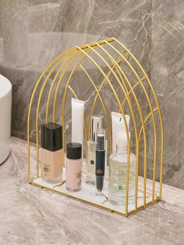 Luxury gold storage rack for bathroom holding various skincare and makeup bottles on marble surface