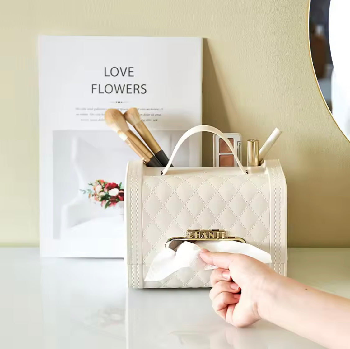 Beige quilted handbag tissue box holder with gold trim used to dispense tissues on a white surface
