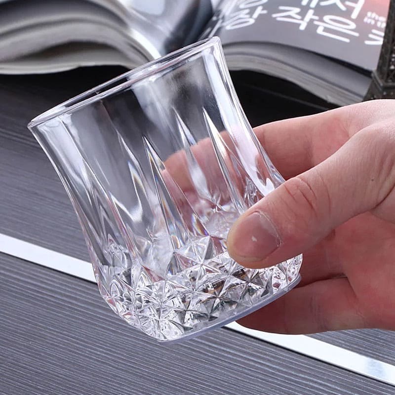 Clear magic light up acrylic mug with faceted design held in hand on a table