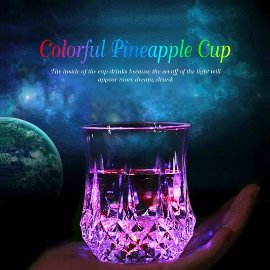 Magic light up acrylic mug glowing with colorful lights held in hand against dark space background