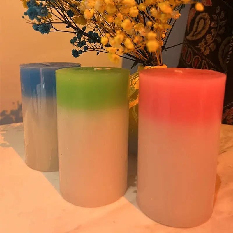 Set of three colorful gradient magic wax mood candles in blue, green, and red on a table with flowers