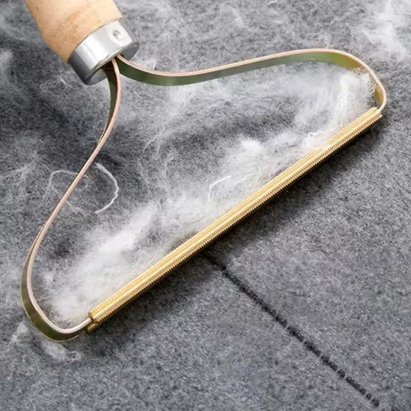 Manual lint remover for clothes with wooden handle removing lint from a gray fabric surface