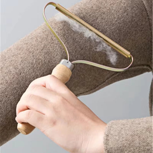 Manual lint remover for clothes with wooden handle removing lint from brown wool fabric