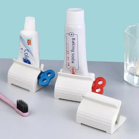 Clarify.pk manual toothpaste squeezer in white with blue and red knobs holding toothpaste and baking soda tubes