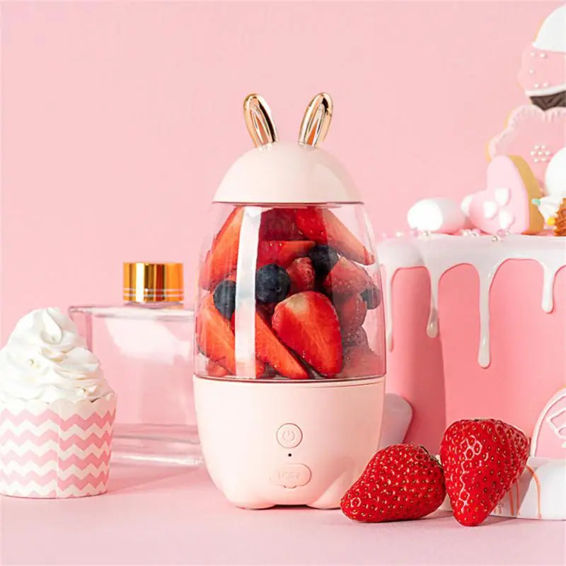 Clarify.pk portable electric juicer in pink with bunny ears blending fresh strawberries and blueberries