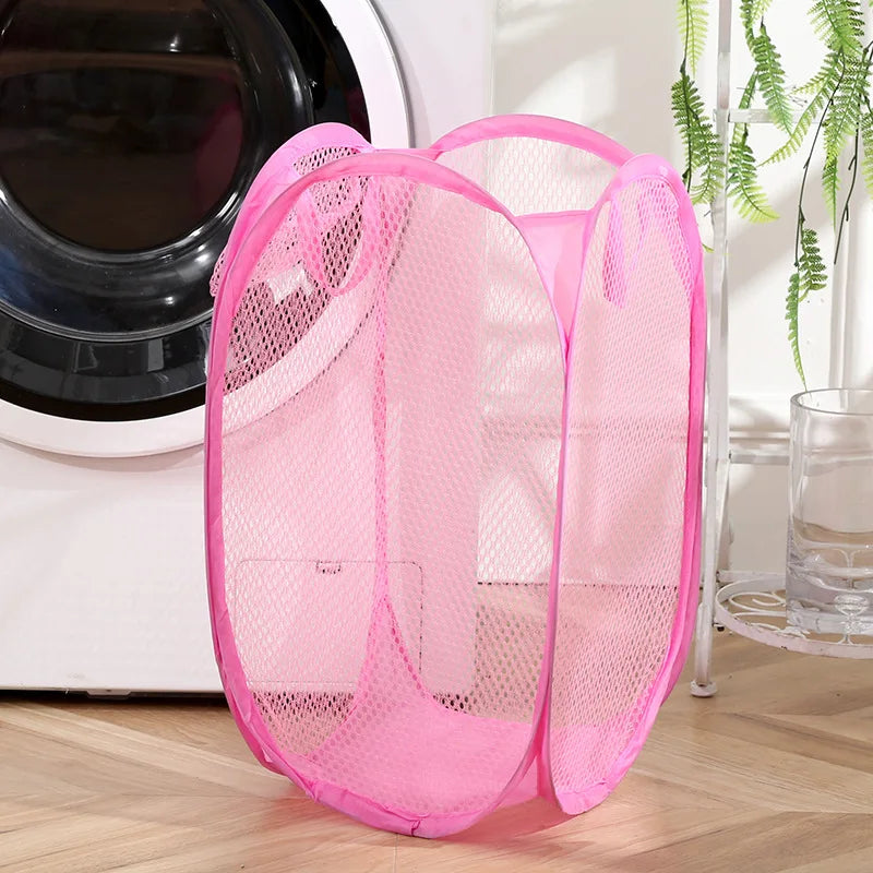 Pink mesh foldable laundry basket from Clarify.pk placed next to a washing machine