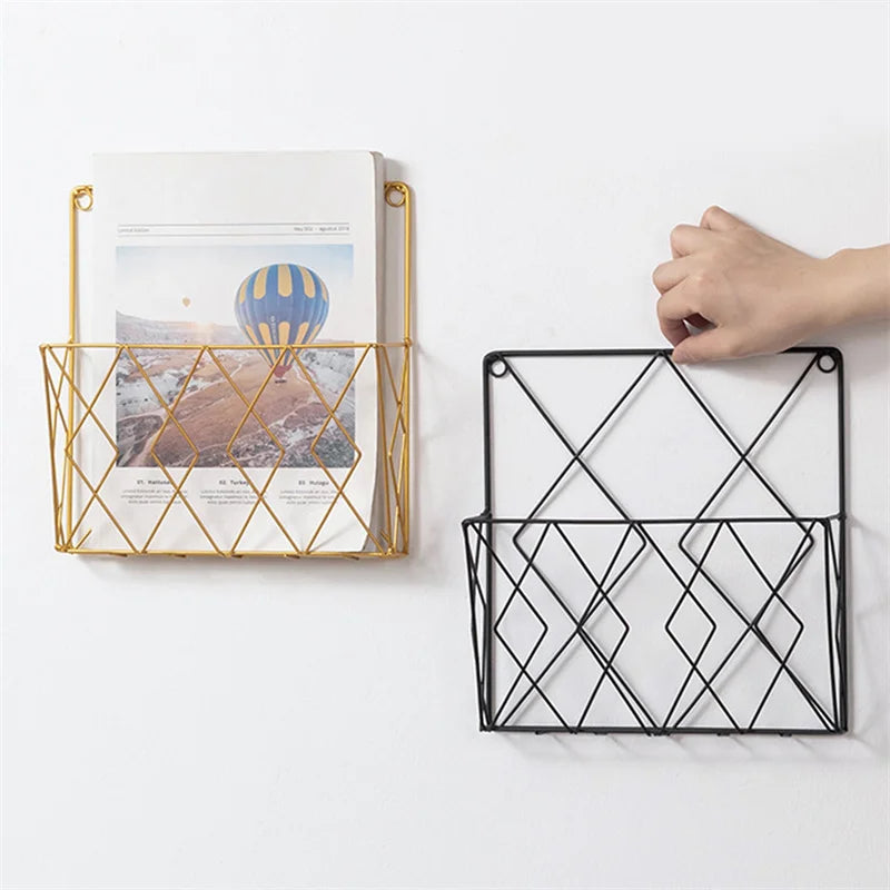 Black and gold metal wall mounted rack holding papers on a white wall