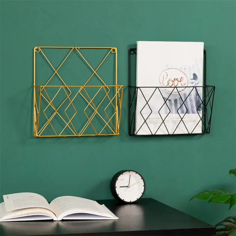 Gold and black metal wall mounted rack with geometric design holding magazines on green wall