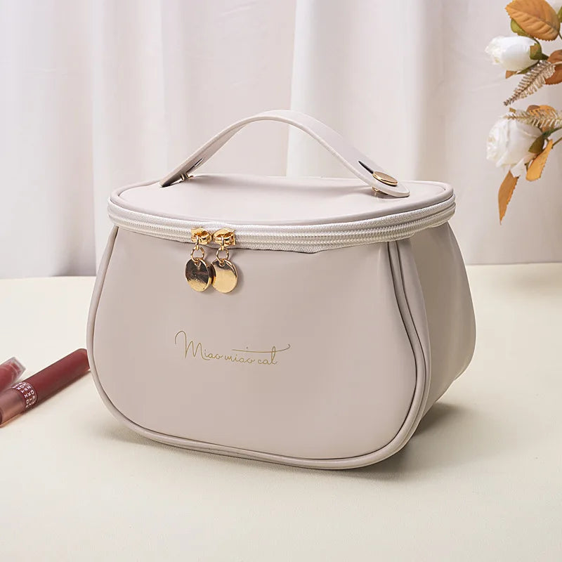 Beige portable makeup case with zipper and gold accents, compact and stylish for travel or daily use