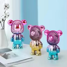 Mini cartoon bear fan in shiny metallic colors including pink, gold, and blue, standing on a desk
