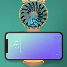 Mini fan with phone stand in beige holding a smartphone in landscape mode on a teal background