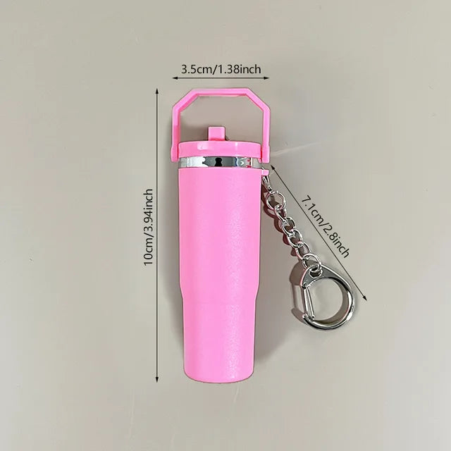 Pink mini tumbler keychain with silver clip and dimensions shown against a beige background
