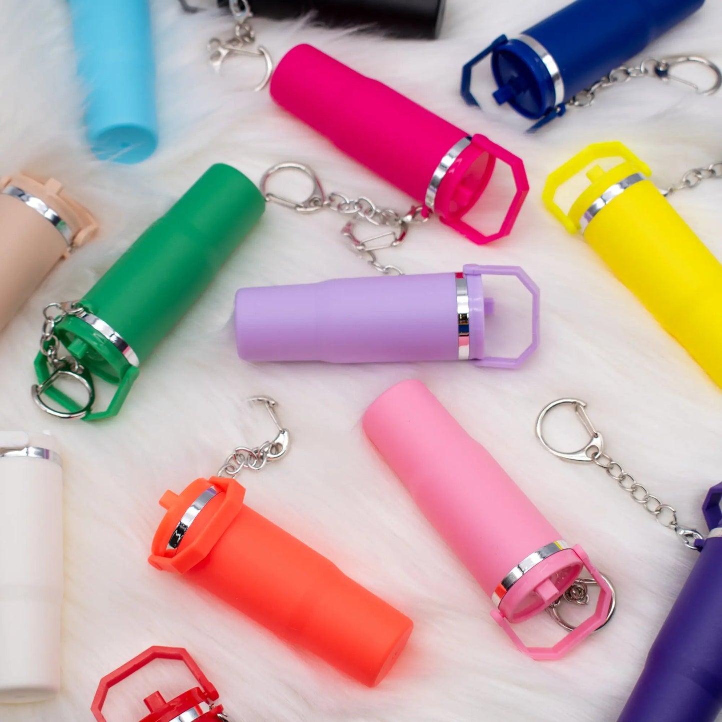 Colorful assorted mini tumbler keychain collection with silver accents and key rings on white background