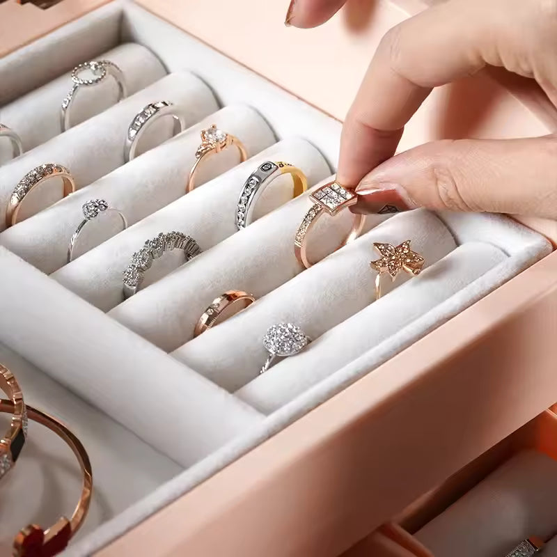 Modern jewelry storage box with drawers holding various rings including gold and silver designs