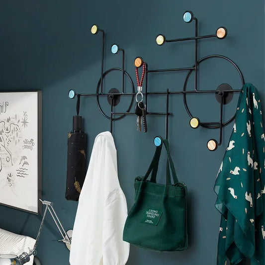 Modern wall mounted coat stand with colorful hooks holding bags, coats, and accessories on a dark wall