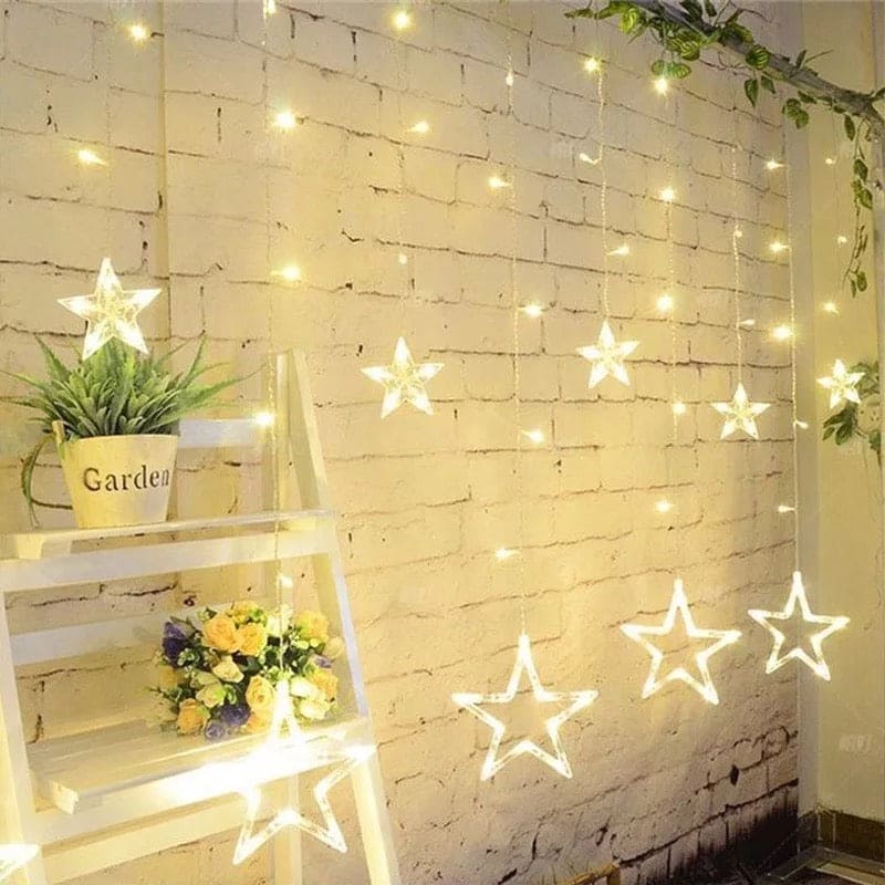 Warm white moon star curtain lights hanging on a brick wall with glowing star shapes and small lights