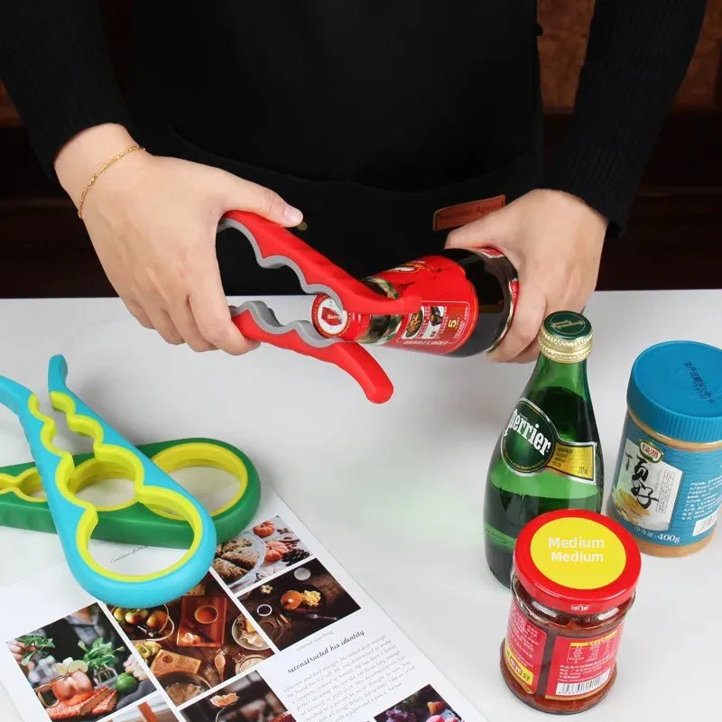 Hands using red multi-functional bottle opener to open a glass bottle with additional openers and jars on table