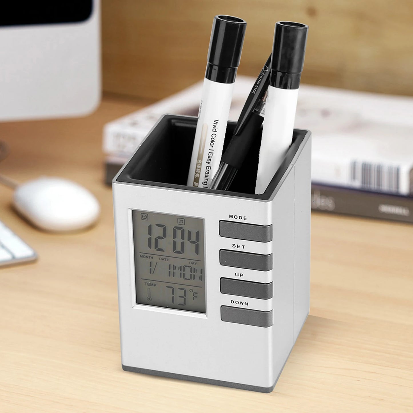 Multifunctional alarm clock with pen holder in silver and black on a wooden desk with digital display