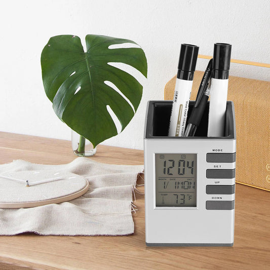 Multifunctional alarm clock with pen holder on wooden desk displaying time temperature and date