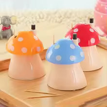 Colorful mushroom toothpick holder set with orange, blue, and red caps on wooden table