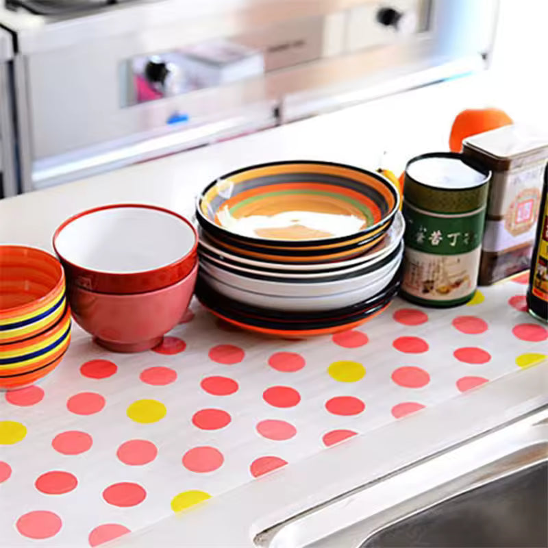 Colorful non-slip cabinet mat for drawers with red and yellow polka dots holding bowls and containers on kitchen counter