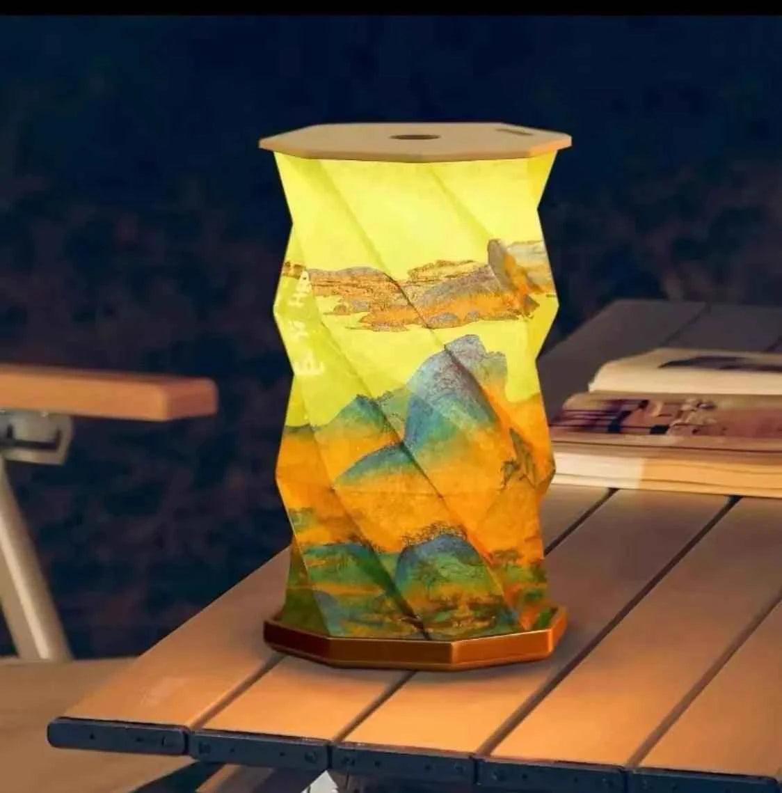 Colorful origami-style LED table lamp with mountain design on wooden base illuminating a night scene