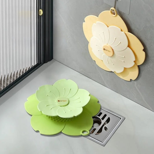 Green and yellow flower-shaped silicone drain cover for bathroom placed near and hanging on sink drain