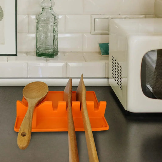 Orange kitchen spoon holder organizing wooden cooking spoons on a kitchen countertop near microwave