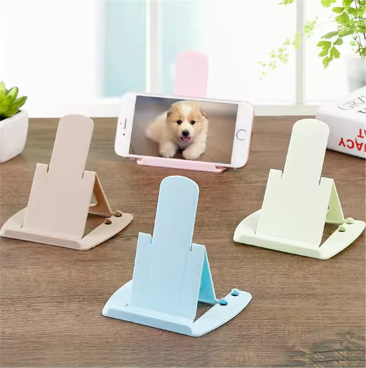 Pack of 4 cell phone stands in pastel colors holding a smartphone on a wooden surface