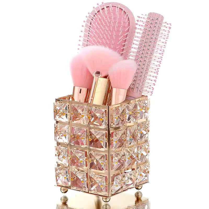 Crystal makeup brush holder with decorative square patterns holding pink brushes and hairbrushes