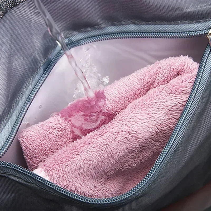 Water-resistant interior of large capacity travel bag with pink towels inside and water pouring