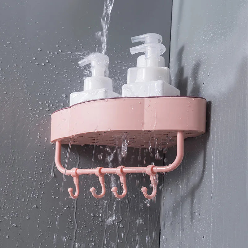 Pink wall-mounted corner shower shelf with hooks holding two white pump bottles in a wet shower