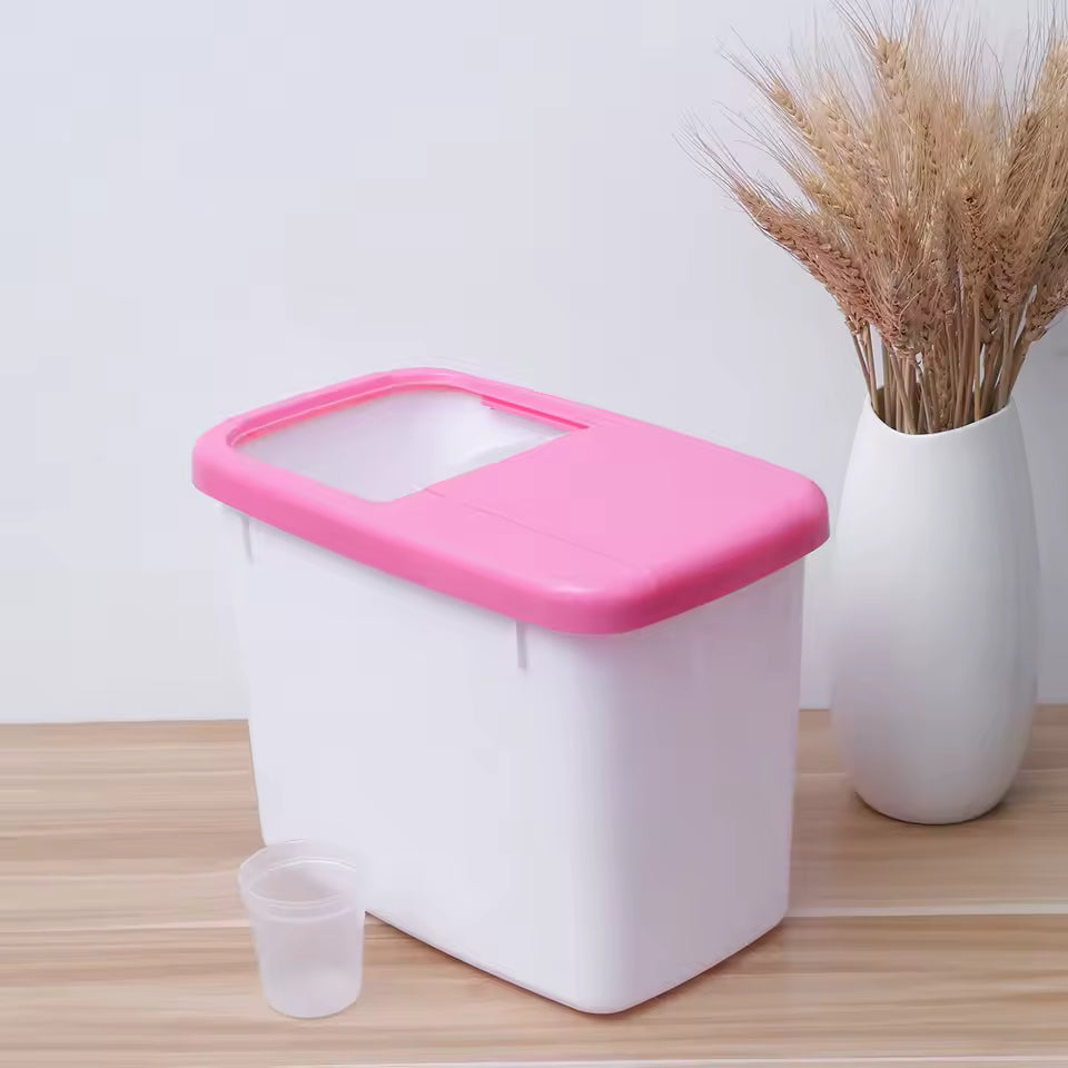 White plastic 10kg rice storage container with pink lid and measuring cup on wooden surface
