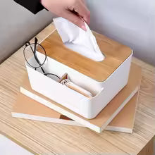 Plastic tissue box with wooden lid and compartments for glasses and remote on a wooden table