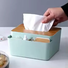 Plastic tissue box with wooden lid and side storage compartments holding office supplies