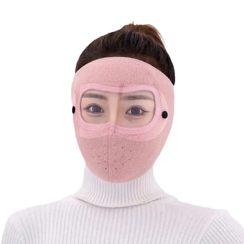 Pink polar fleece winter mask with goggles worn by person in white turtleneck sweater
